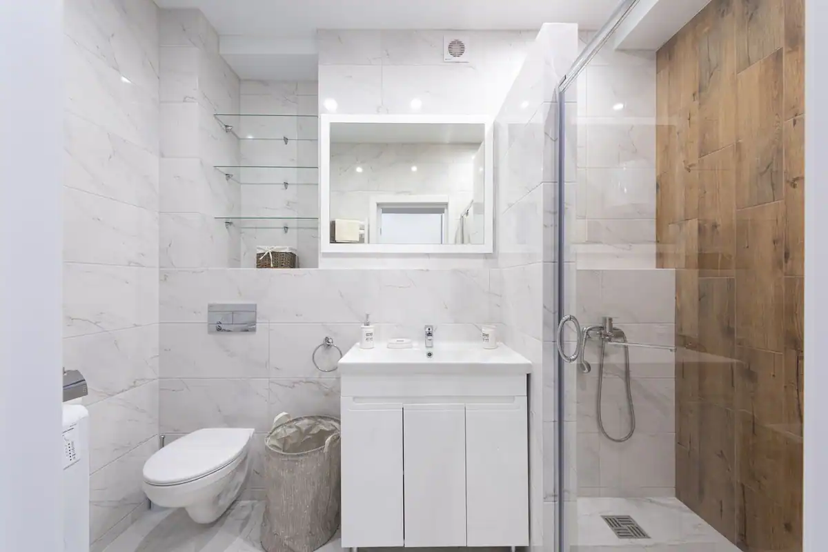 Baie minimalistă cu plăci de marmură și cabină de duș din sticlă