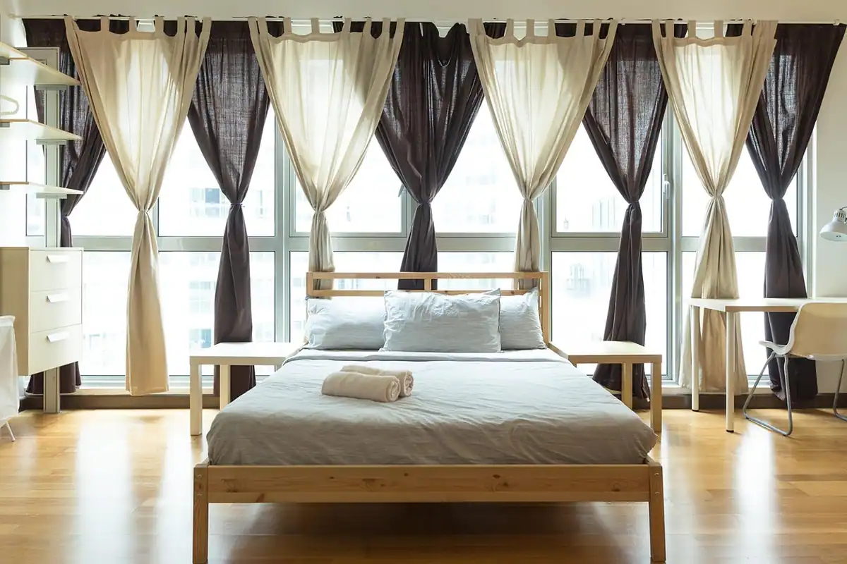 Interior de cameră ordonat, fără fire la vedere, cu mobilier simplu lângă fereastră