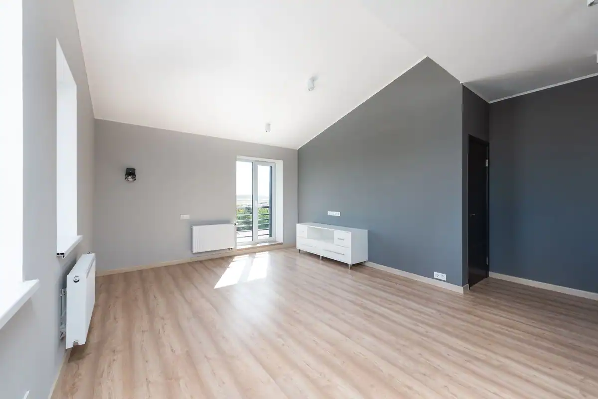Apartament gol cu parchet din lemn și ferestre mari, pregătit pentru zugrăvit