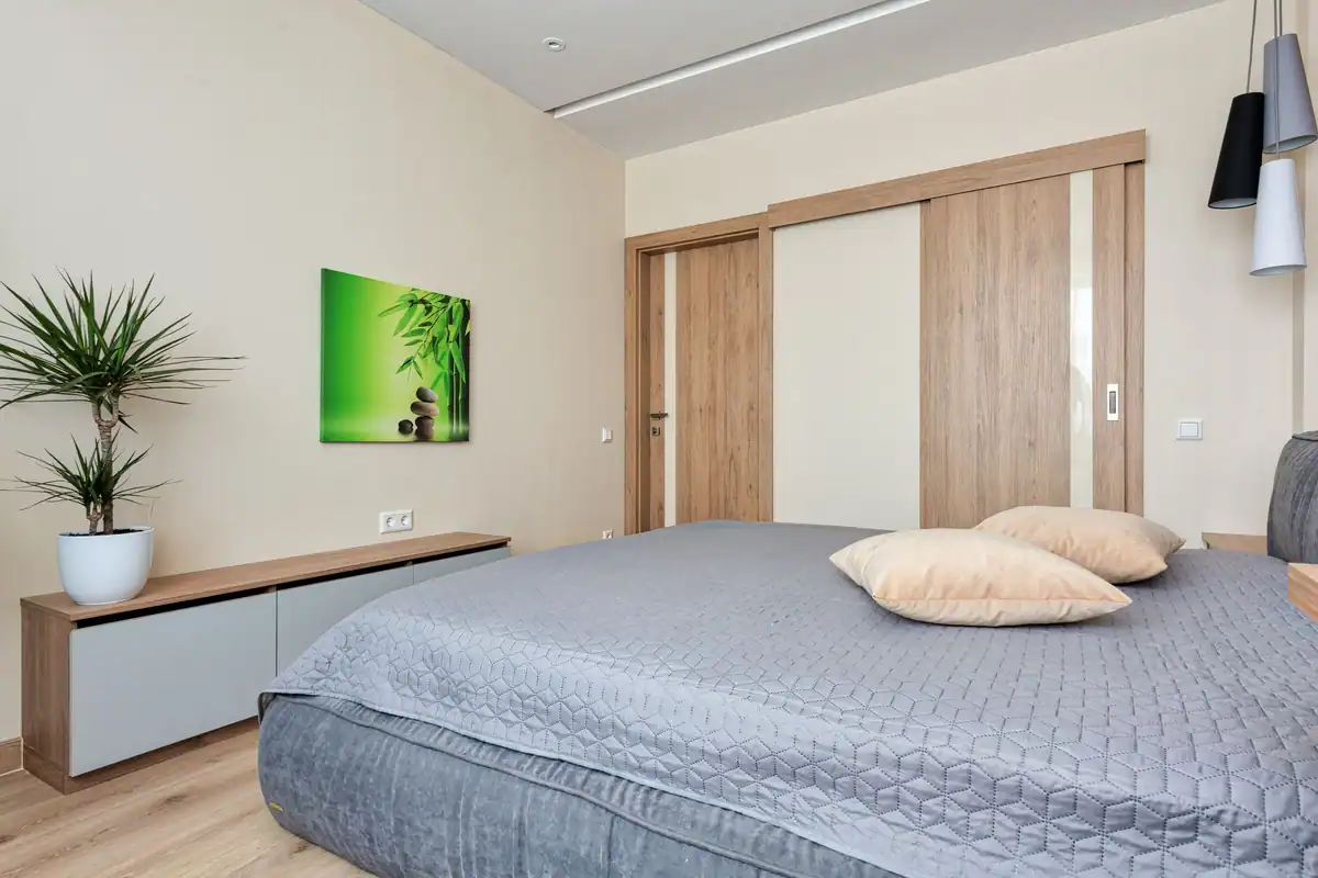 Dormitor modern cu uși glisante din lemn, plantă de apartament și așternuturi confortabile