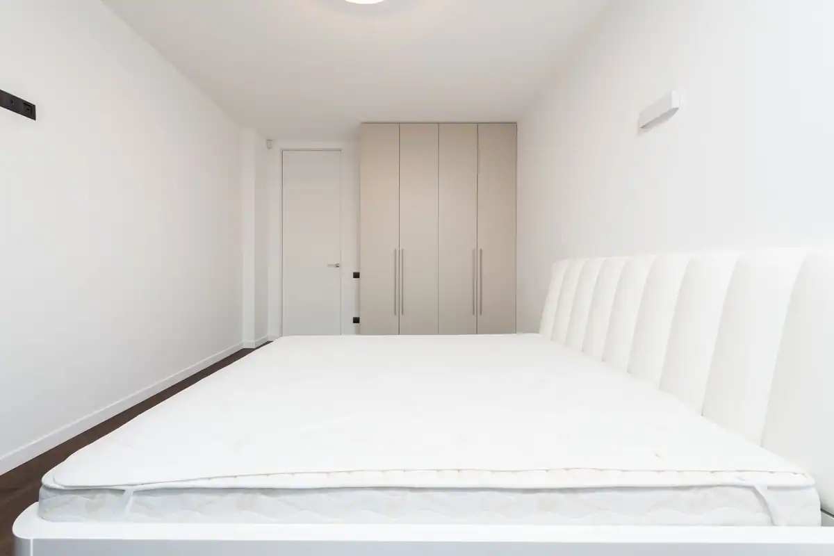 Dormitor minimalist cu saltea albă și dulap modern în lumină blândă