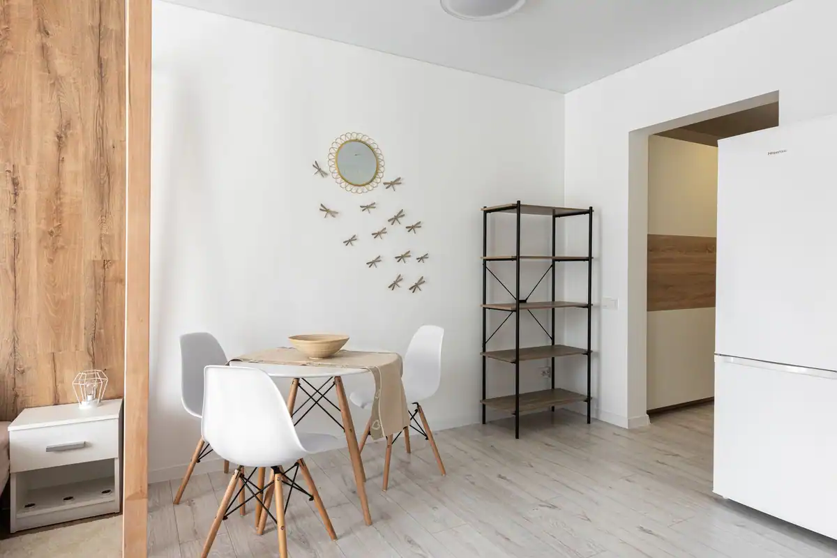 Sufragerie cu masă și scaune, oglindă și decor pe perete