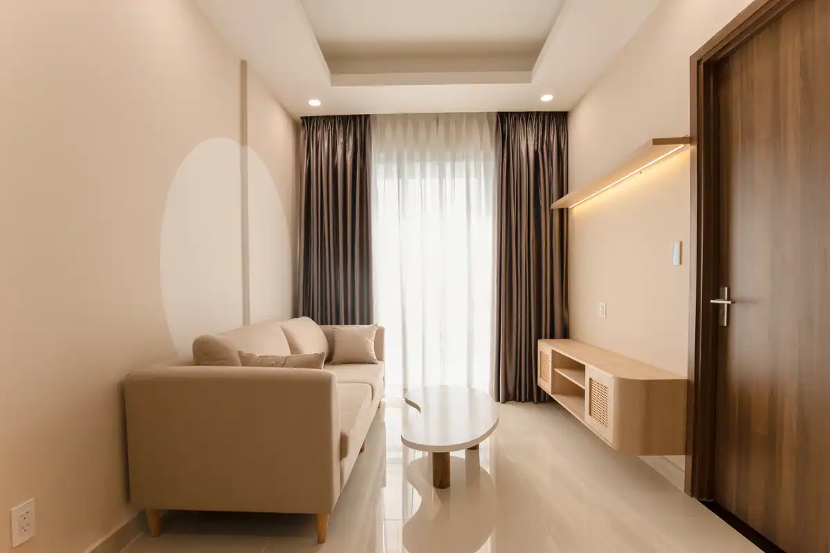 Living minimalist cu canapea bej, masă modernă și lumină blândă