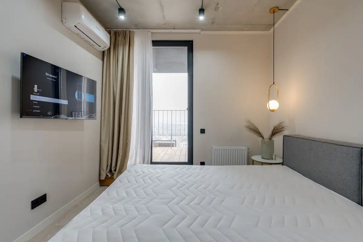 Dormitor minimalist cu balcon, televizor cu ecran plat și iluminat discret