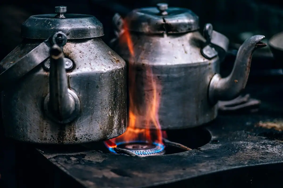 Flacără albastră la arzătorul unei plite pe gaz, cu un ceainic deasupra