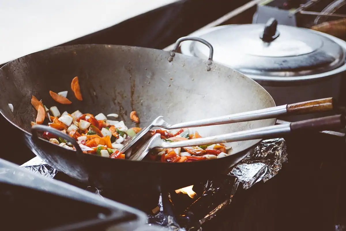 Sertare largi de bucătărie trase afară, cu oale și tigăi aranjate în ele