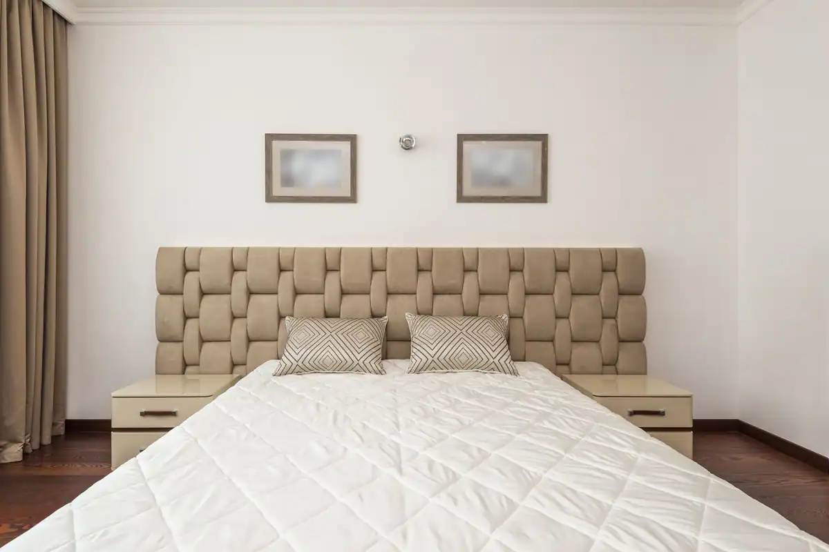 Dormitor bej cu tăblie capitonată, perne pufoase și decor minimalist